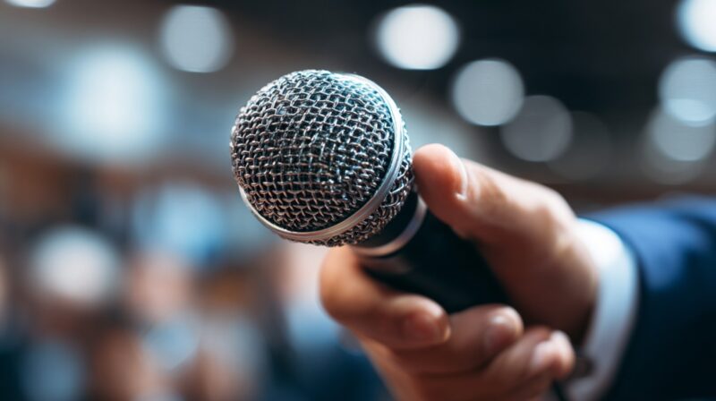 Close-up of a hand holding a microphone, ready for a speech or presentation