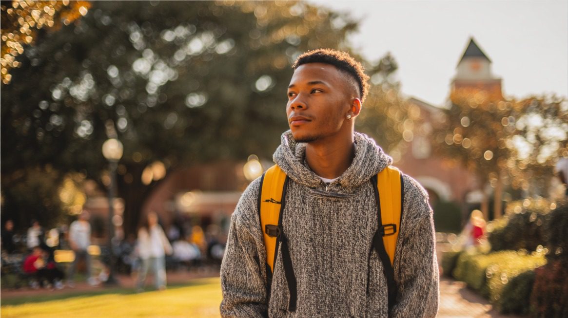 College student with backpack looking thoughtful on a sunny campus