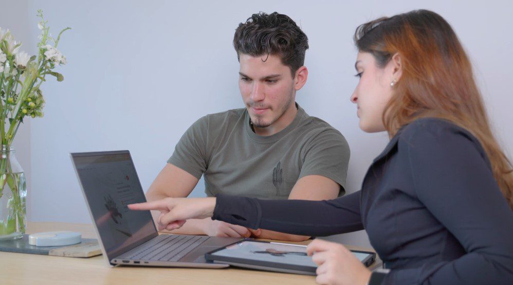 A collaborative discussion unfolds as two individuals review data on a laptop