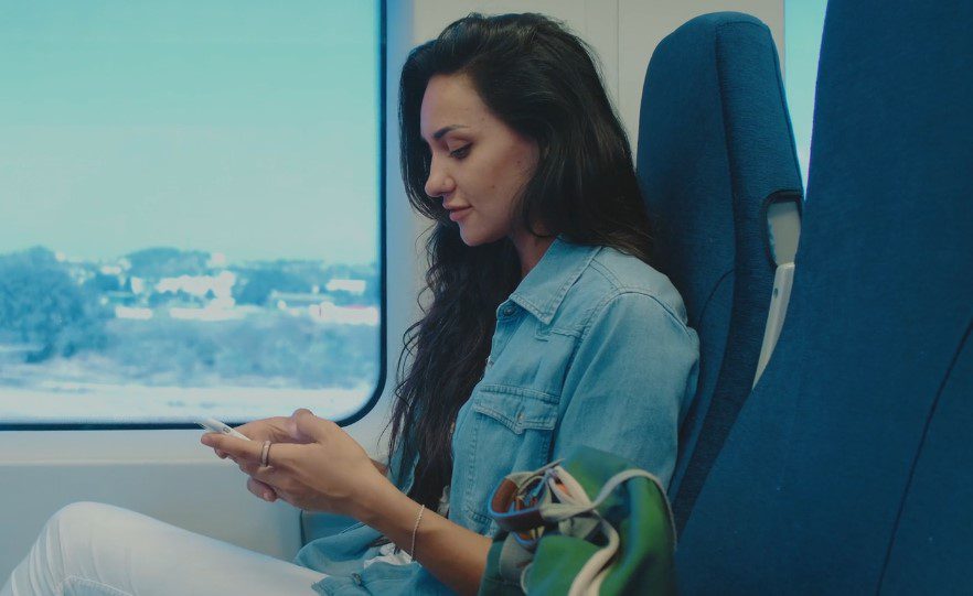 A woman sitting on a train, focused on her phone