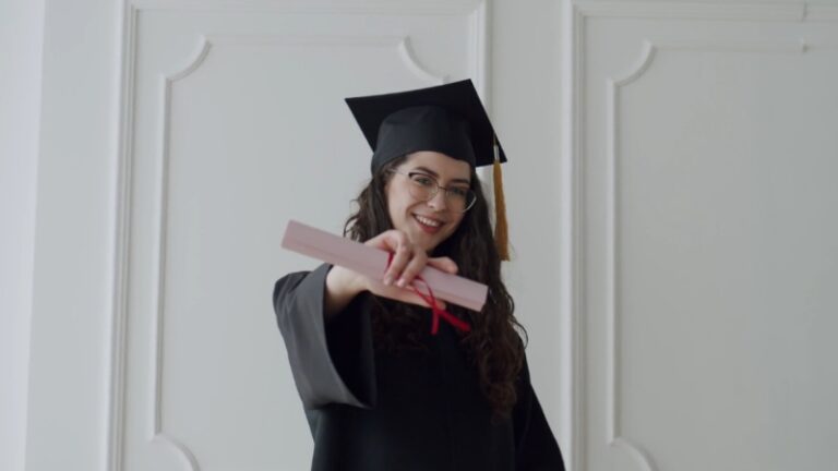 Woman in graduation cap and gown holding a diploma for graduate school applications