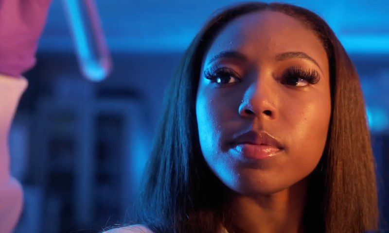 Close-up portrait of a woman in a laboratory setting illuminated by cool blue light