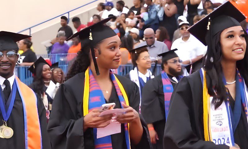 A group of Langston University graduates stands together, proudly wearing their caps and gowns